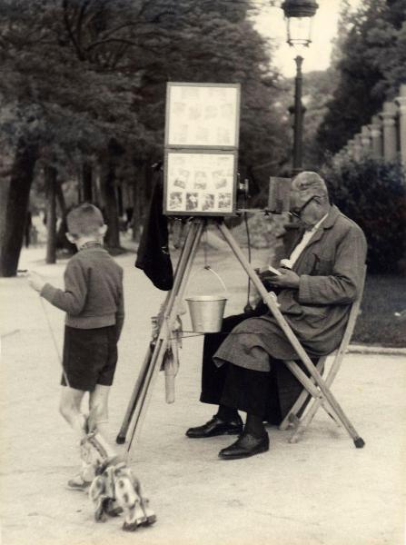 Spagna - Madrid - Paseo del Prado - Fotografo ambulante seduto con macchina fotografica su cavalletto - Bambino con cavallino giocattolo