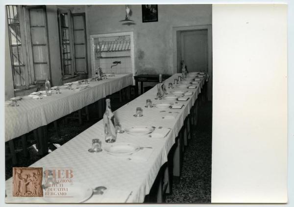 Istituto Divino Redentore - Bergamo: Borgo Santa Caterina - Interno - Sala da pranzo - Due tavoli apparecchiati: piatti, bicchieri, posate - Bottiglie di acqua - Lavandino - Finestre aperte