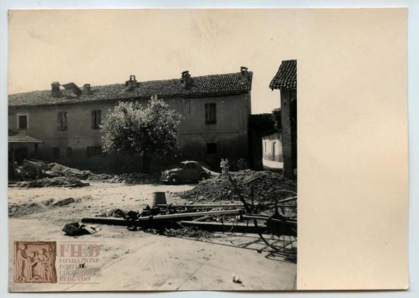 Rustici - Provincia di Bergamo - Misano - Cascina: esterno - Cortile - Una donna con in braccio un bambino - Auto parcheggiata - Cumuli di terra per lavori