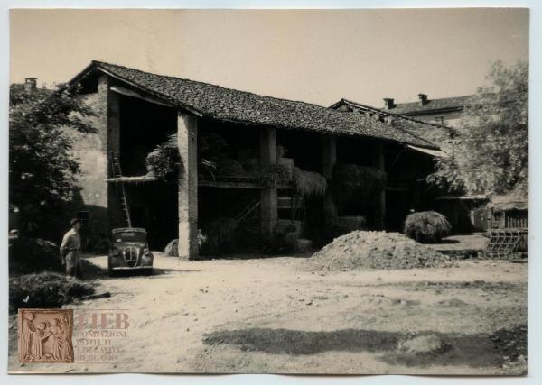 Rustici - Provincia di Bergamo - Misano - Cascina: esterno - Cortile - Un uomo accanto ad un auto parcheggiata - Stalla grande - Fieno