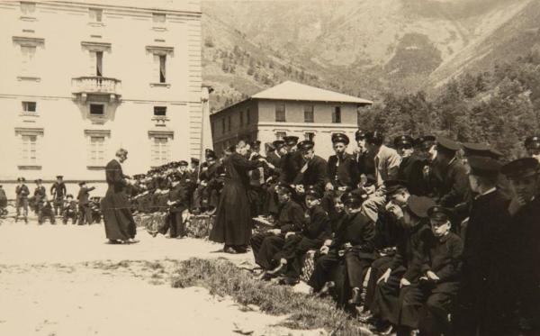 Biella: Oropa - Santuario di Oropa - Esterno - Bambini, ragazzi sordi, allievi del Pio Istituto dei Sordi, seduti, Monsignore Giulio Broggi e altro sacerdote - Pranzo - Pellegrinaggio