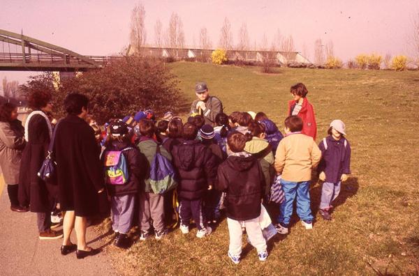 Sesto San Giovanni - Parco Nord, settore Est - Gruppo di bambini di una scuola primara ascoltano un guardiaparco - Sullo sfondo la passerella ciclopedonale Clerici e l'area industriale al confine del Parco / Educazione ambientale - Attività didattica