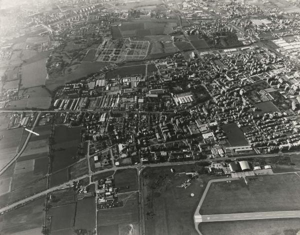 Bresso / Milano / Cormano - Veduta aerea da est a ovest sull'area poi occupata dal Parco Nord, settore Aeroporto, Montagnetta, Bresso Sud, Niguarda, Bruzzano, Brusuglio / Aeroporto di Bresso - Pista di atterraggio - Via XX Settembre - Palazzi - Campi - Palazzi - Cimitero di Bruzzano