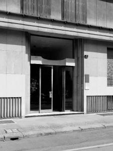 La fascia basamentale con il portone d'ingresso in ferro e vetro, impreziosito da tre fasce ortogonali di strombature laterali - fotografia di Sartori, Alessandro (2016)