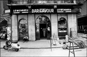 Milano - Via Santa Maria alla Porta angolo via Brisa - Bar Cavour - Uomo seduto a terra davanti ad una vetrina - Uomo all'ìinterno del bar - Insegne al neon - Insegna birra Lowenbrau - Motorino parcheggiato: Piaggio Vespa ET3 - Lavori stradali