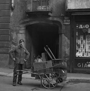 Milano - Via del Torchio 16 - Strada - Ritratto maschile: netturbino con carretto della spazzatura - Entrata ad arco con cornicione decorativo - Vetrina di un negozio A&O con esposto il detergente Biol