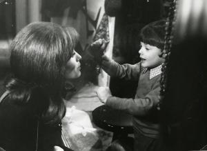 Scena del film "Io, Emmanuelle" - Regia Cesare Canevari, 1969 - Erika Blanc, accovacciata, osserva un bambino al di là di una vetrina che, con il pugno sul vetro, richiama la sua attenzione.